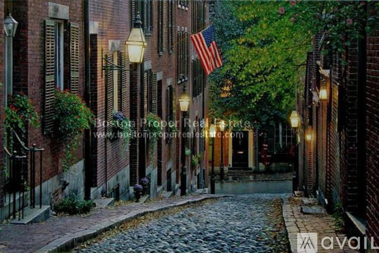 A cobblestone street lined with brick buildings and an American flag hanging from one of the buildings.