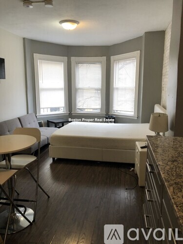 A bedroom with a bed, a table and chairs, and a window.