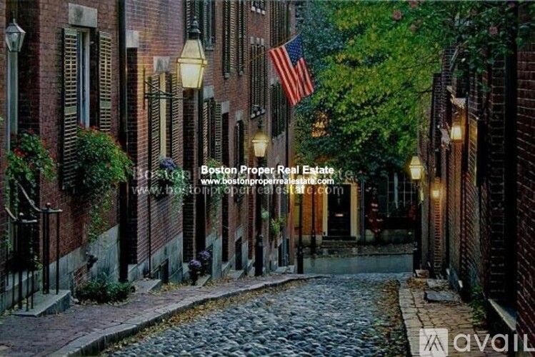 A cobblestone street in a residential area with a flag hanging from a building.