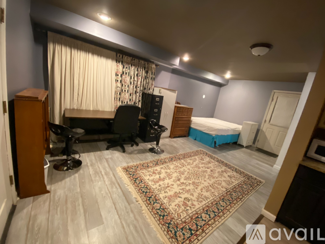 A room with a bed, a desk, a chair, and a rug.