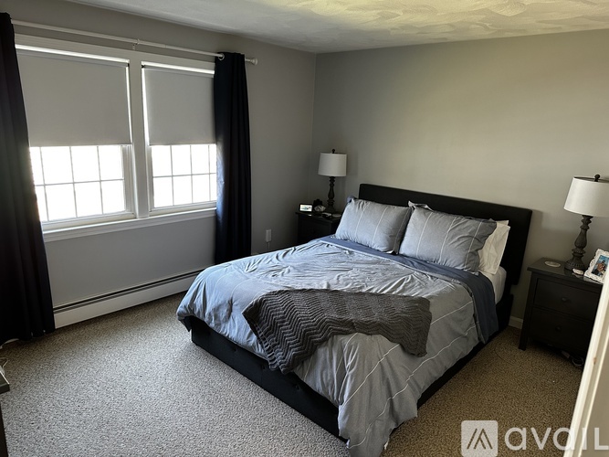 A bedroom with a bed, nightstand, and window.