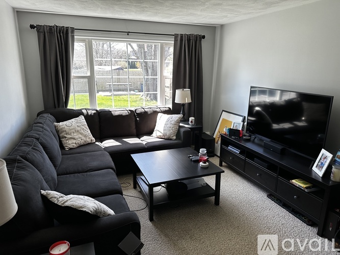 A black leather sofa with a grey cushion and a black coffee table in front of a television.