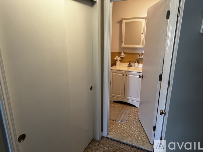 A bathroom with a sink and mirror is visible through an open door.