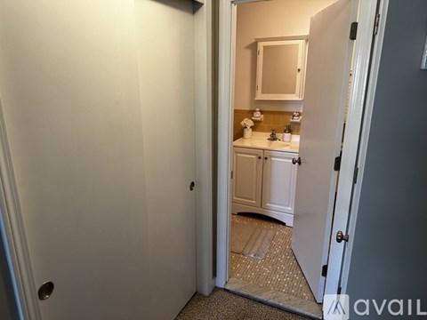 A bathroom with a sink and mirror is visible through an open door.
