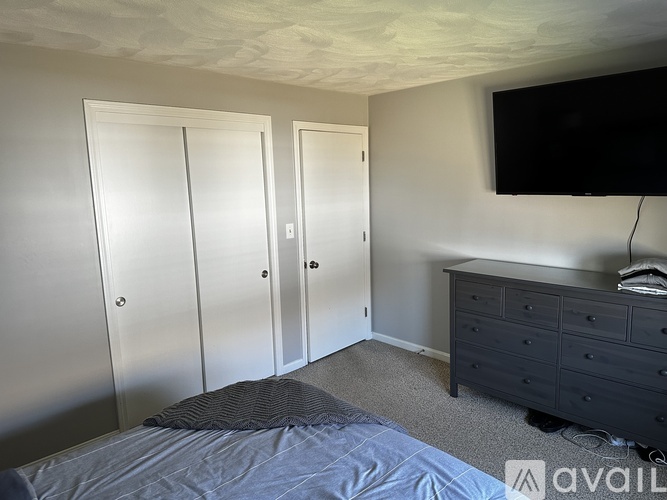 A bedroom with a bed, dresser, and a television.