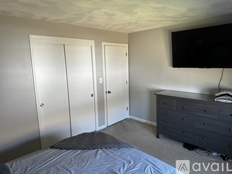 A bedroom with a bed, dresser, and a television.