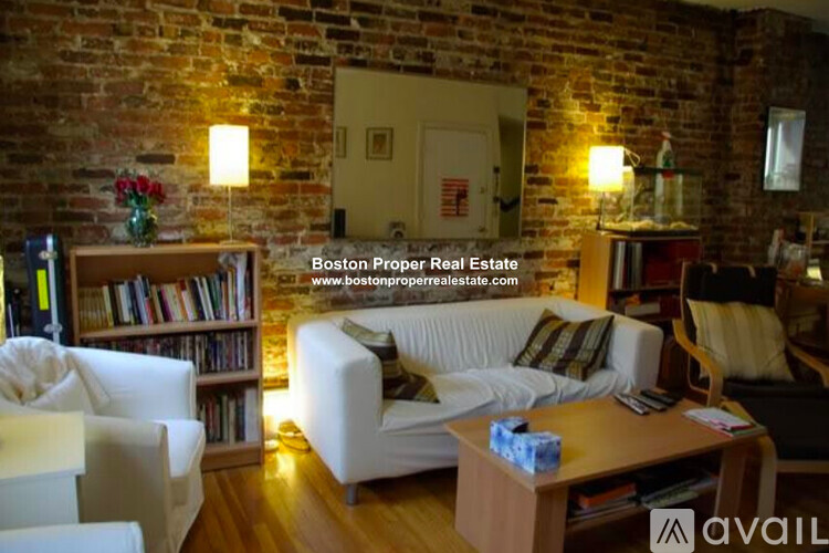 A living room with a brick wall and a white couch.