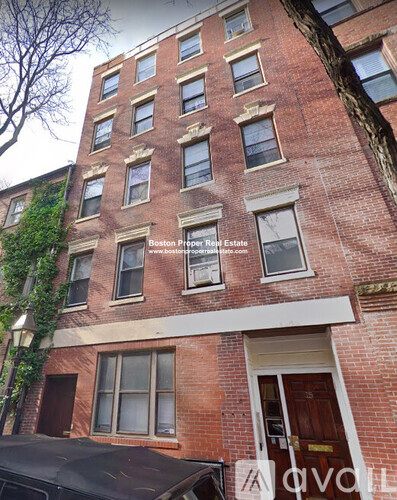 A red brick building with a black car parked in front.