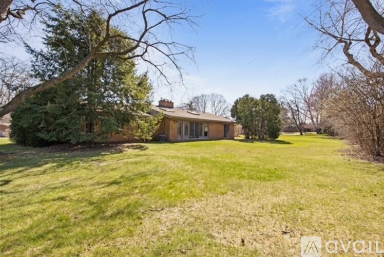 A house is for sale in a grassy area with trees.