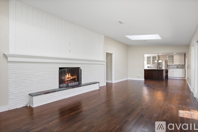 A spacious room with a fireplace and wooden floors.