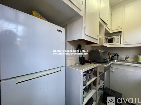 A kitchen with a white fridge and a white cabinet above the counter.