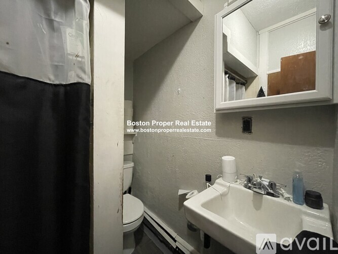 A bathroom with a toilet, sink, and mirror.