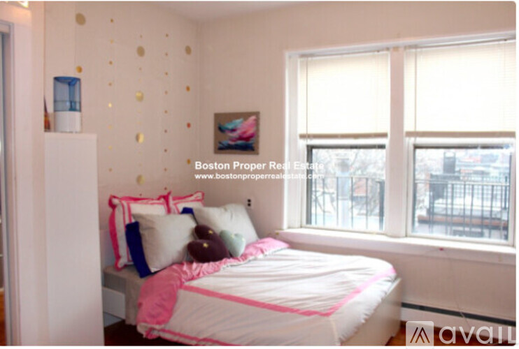 A bedroom with a bed, pillows, and a window.