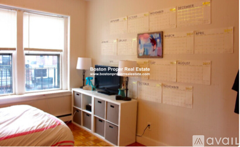 A bedroom with a bed, window, and a wall with a calendar on it.