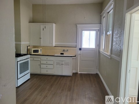 A kitchen with white cabinets and a microwave above the stove.