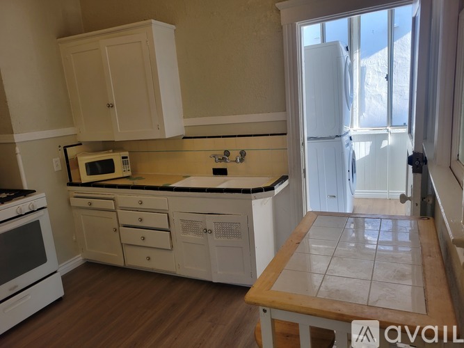 A kitchen with white appliances and wooden floors.