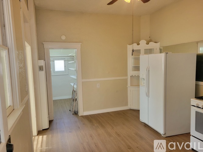 A kitchen with a white refrigerator and a wooden floor.