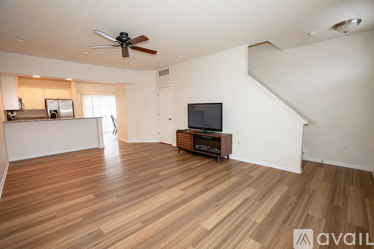 A spacious living room with wooden flooring and a ceiling fan.