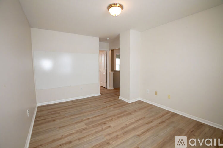 A spacious room with wooden flooring and white walls.