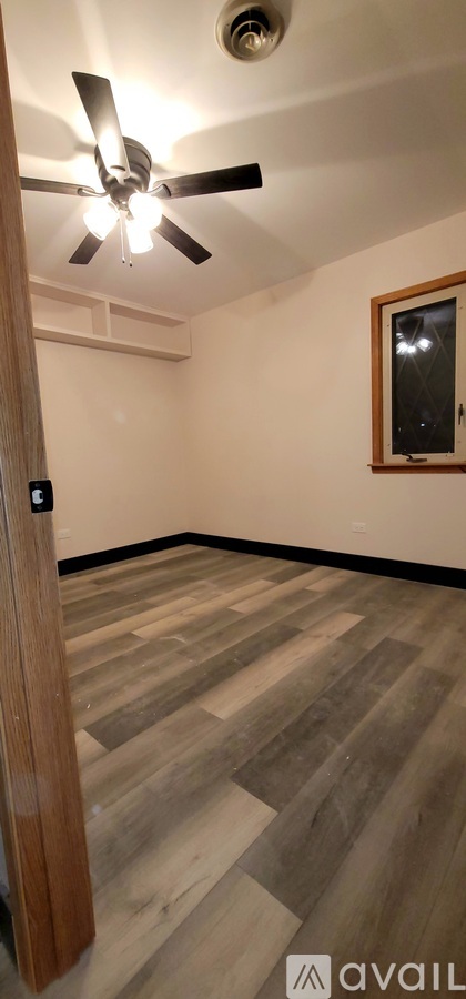 A room with a ceiling fan and wooden flooring.