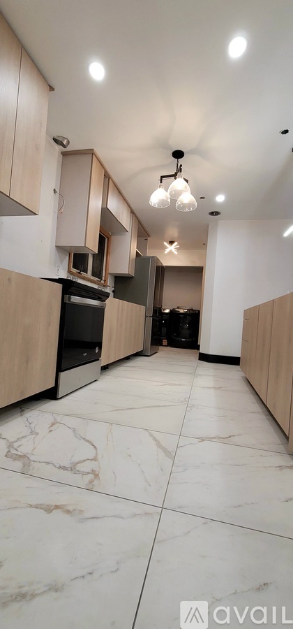 A kitchen with wooden cabinets and marble flooring.