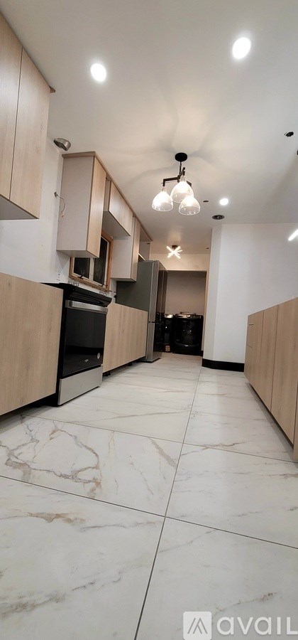 A kitchen with wooden cabinets and marble flooring.