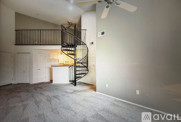 A room with a spiral staircase and a fan.