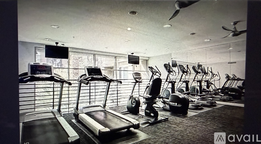 A gym with treadmills, exercise bikes, and a television.