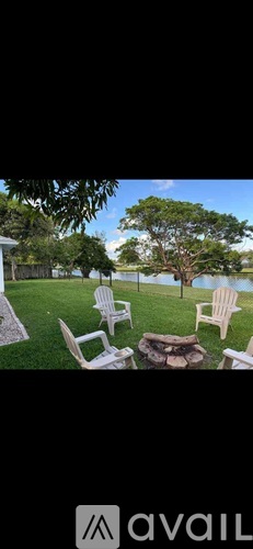 A backyard with white chairs and a tree.