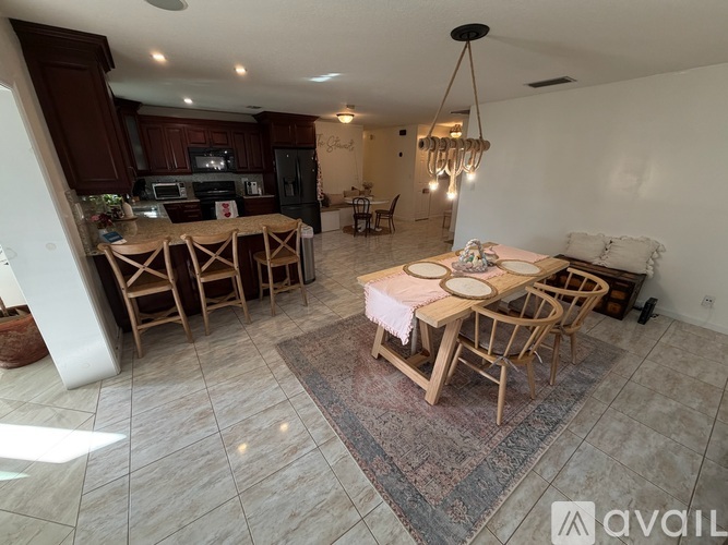 A dining room with a table set for two and a kitchen area in the background.