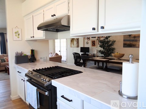 A modern kitchen with a black stove top oven and white cabinets.