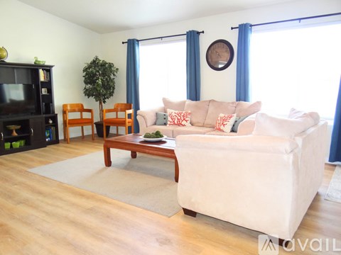 A living room with a white couch, a wooden coffee table, and a TV.