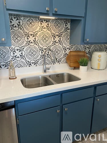 A kitchen with blue cabinets and a patterned backsplash.
