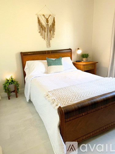 A bedroom with a large bed and a small plant on the side table.