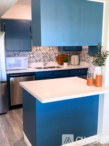 A kitchen with blue cabinets and a white counter.