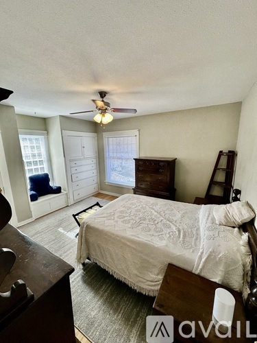 A bedroom with a bed, dresser, and a ceiling fan.