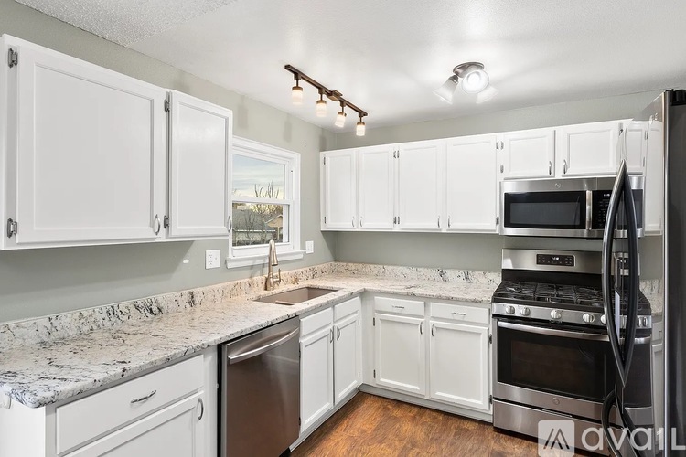 A kitchen with white cabinets and a granite countertop.