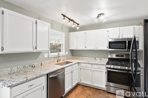 A kitchen with white cabinets and a granite countertop.