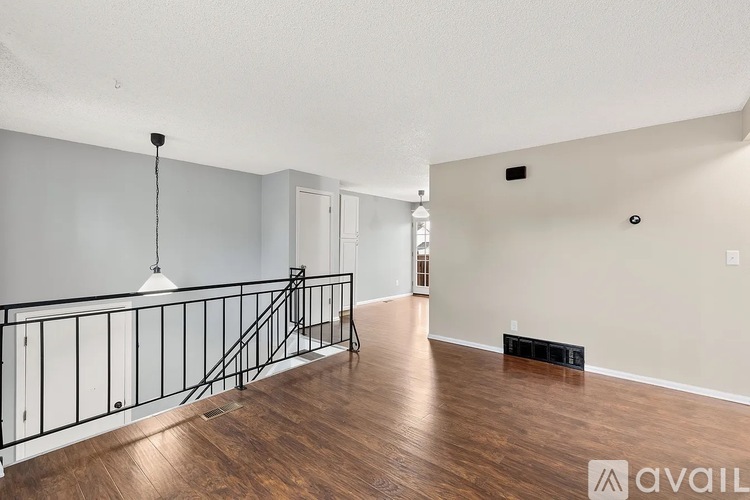 A spacious room with wooden floors and a balcony with a black railing.