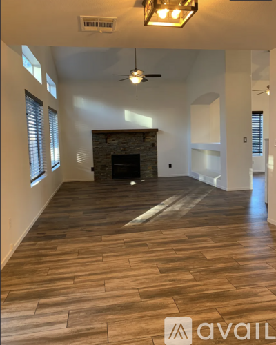 A spacious living room with a fireplace and wood flooring.