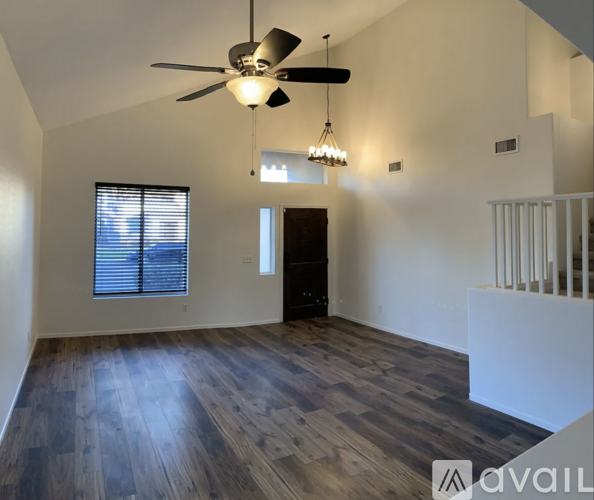 A spacious room with a ceiling fan and wooden flooring.