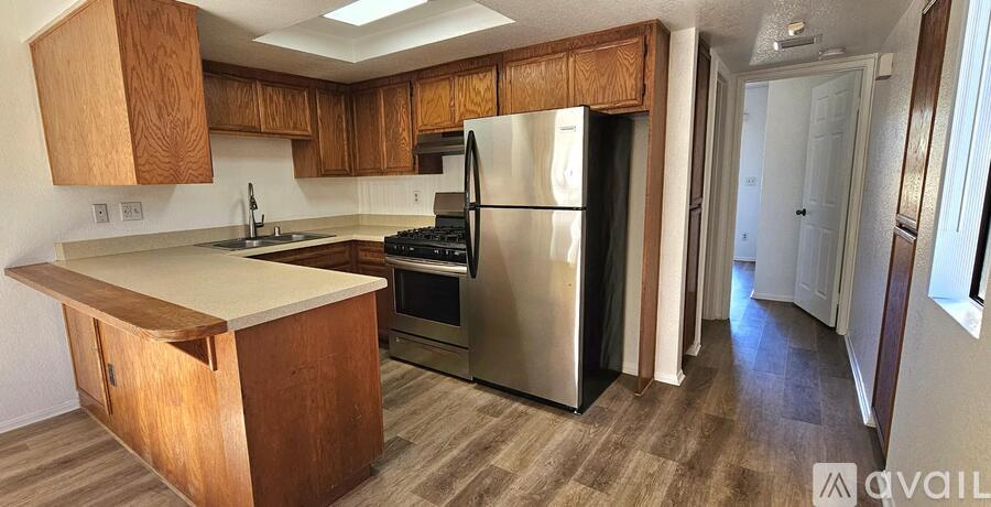 A kitchen with wooden cabinets and a stainless steel refrigerator.