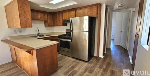 A kitchen with wooden cabinets and a stainless steel refrigerator.