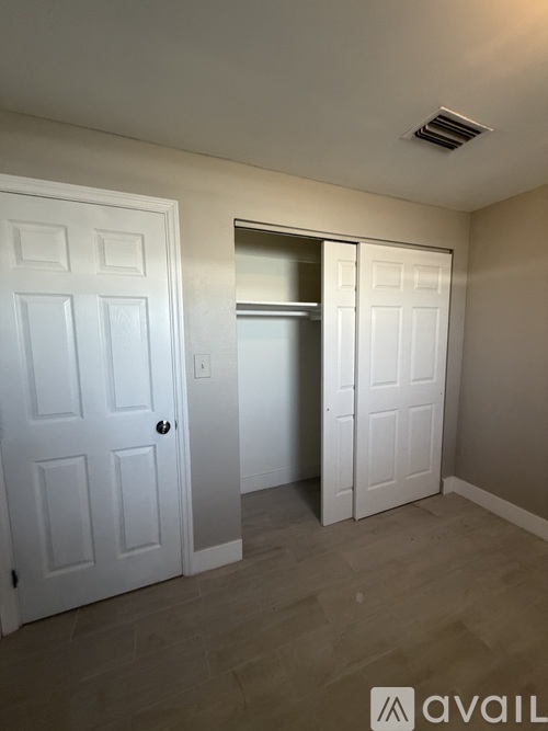 A room with a white door and a white closet with a mirror.