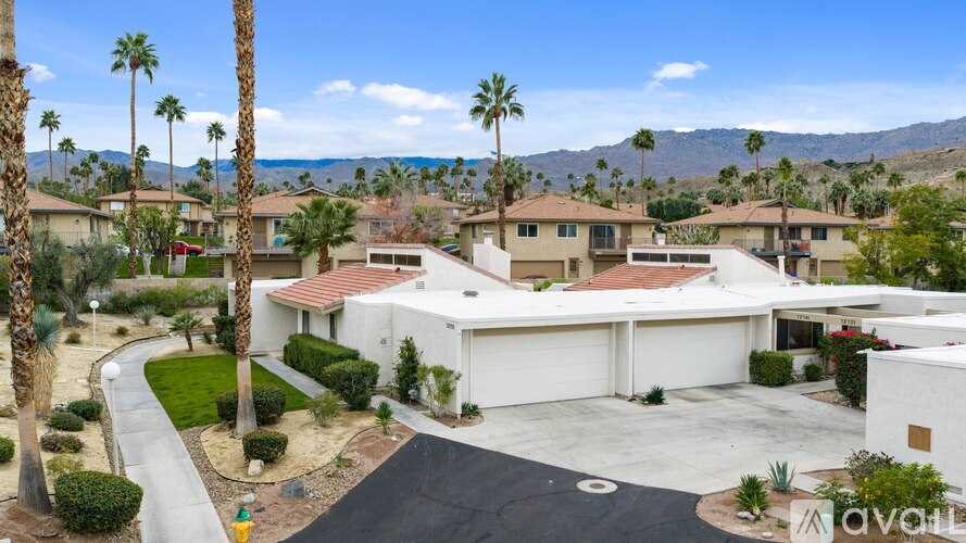 A house with a driveway and palm trees in front.