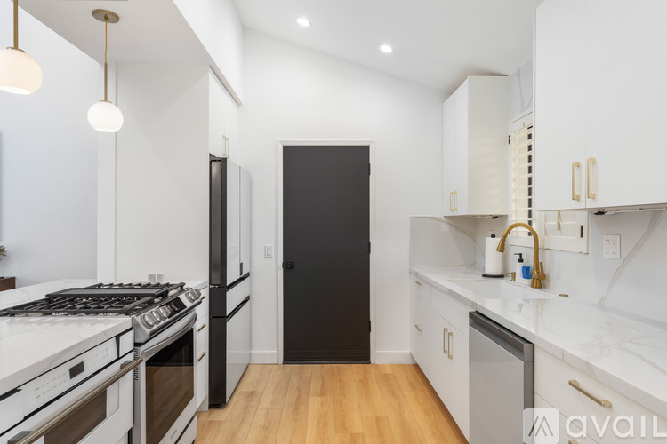 A modern kitchen with white cabinets and a black door.