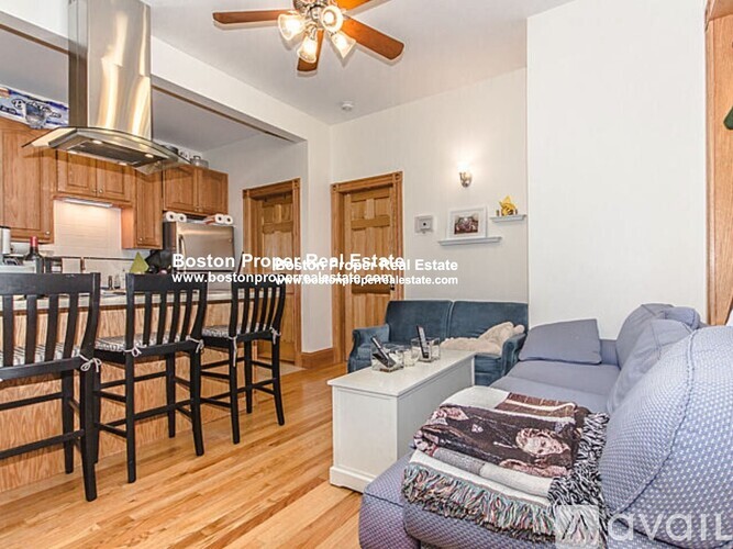 A living room with a couch, chairs, and a ceiling fan.