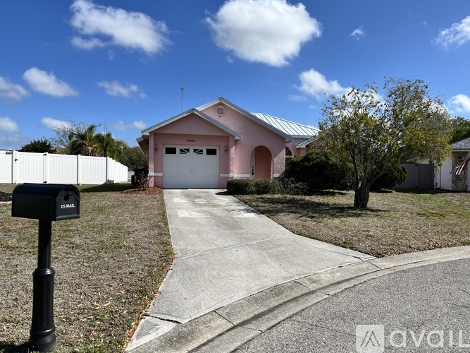A pink house with a black mailbox on a sunny day.
