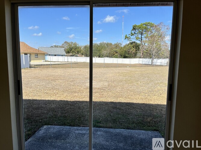 A view from inside a room looking out to a yard with a fence and trees.