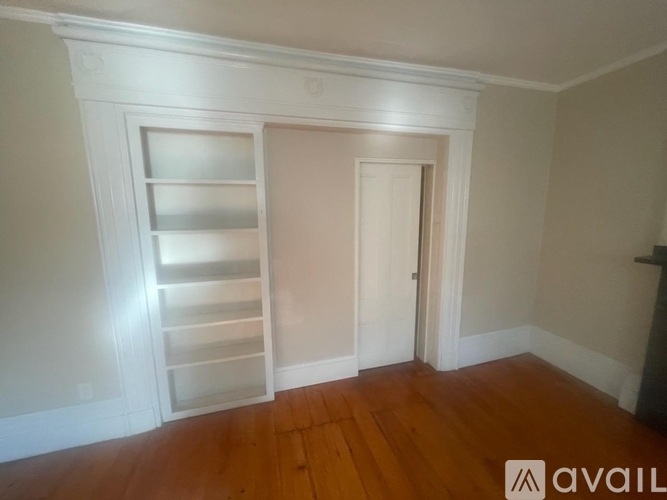 A room with a white door and a white shelf unit.
